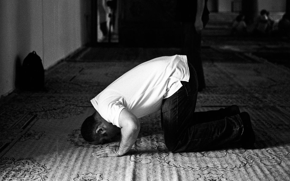 A young man kneeling in prayer at his local mosque